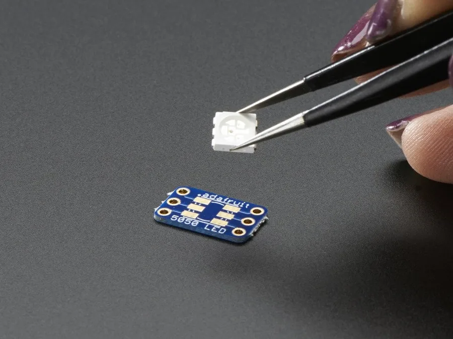 The RGB LED used in the pupil: a 5050 package held in tweezers above its Adafruit carrier board